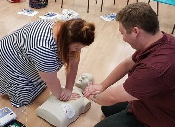 Participants practicing CPR on a manikin during onsite first aid training.