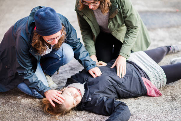 Two women are checking the consciousness of a kid and evaluating the situations to start their first aid steps